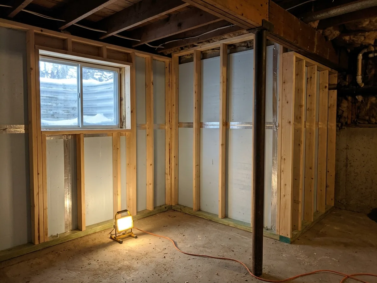 Basement foundation wall with rigid foam board and a new 2x4 stud wall on a pressure-treated bottom plate
